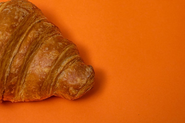 Croissant fresco aislado en concepto de desayuno francés de tablero naranja