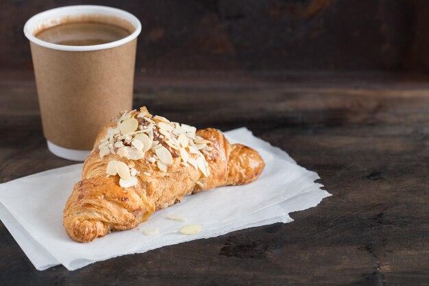 Croissant fresco y café en una taza de papel