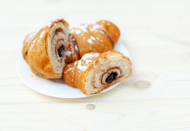 Croissant fresco con chocolate en la mesa de madera blanca