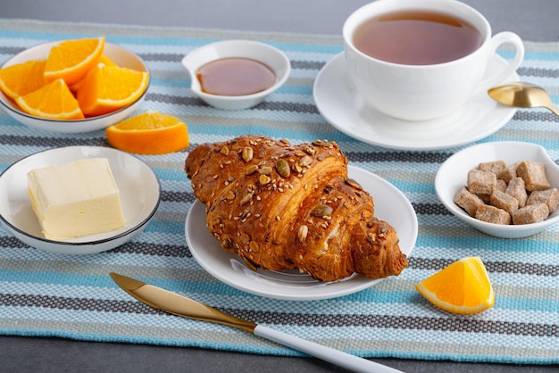 Croissant fresco com manteiga e chá laranja no café da manhã