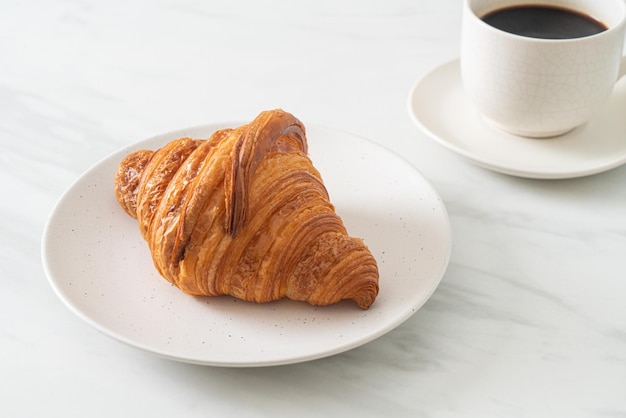 croissant fresco na chapa branca com café preto