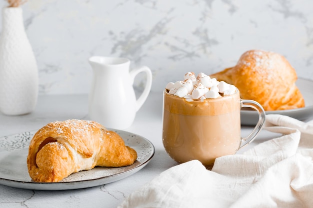 Croissant fresco en un plato y una gran taza de café en la mesa Estilo de vida de desayuno casero