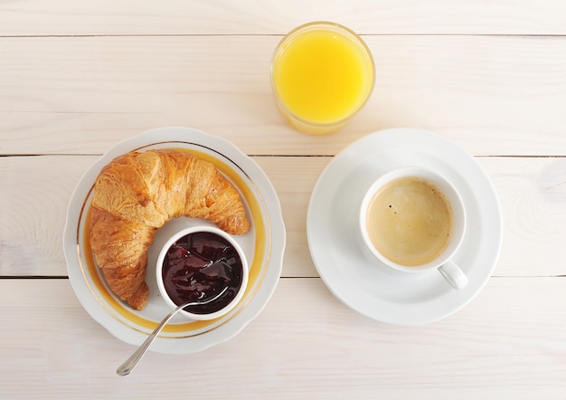 Croissant, geléia, café e suco de laranja na superfície de madeira