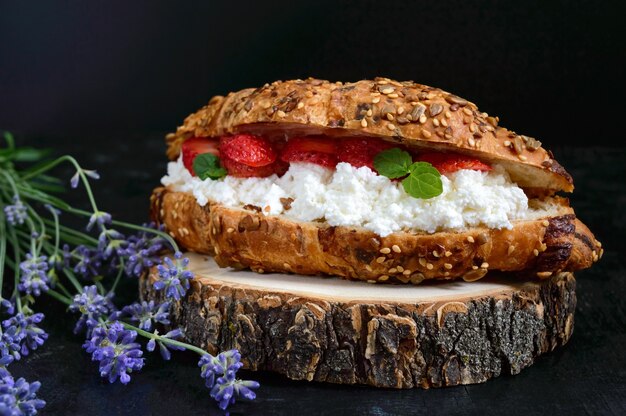 Croissant grande de cereais com queijo cottage e morangos frescos em um fundo escuro