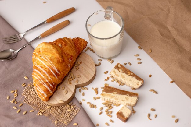 Croissant grande, un vaso de leche y rodajas de sorbete dulce.