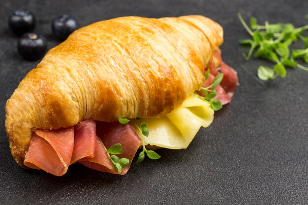 Croissant con jamón y queso y verduras. Superficie negra. Vista superior