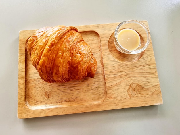 El croissant con leche condensada azucarada en un plato de madera
