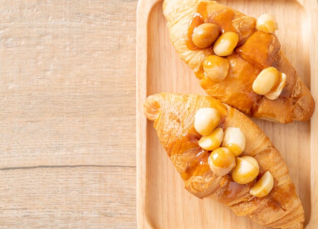 Croissant con macadamia y caramelo sobre placa de madera