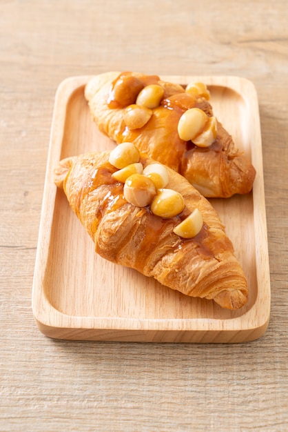 Croissant con macadamia y caramelo sobre placa de madera