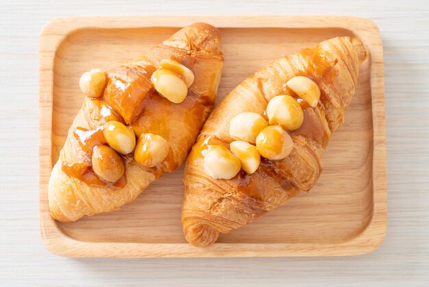 Croissant con macadamia y caramelo sobre placa de madera