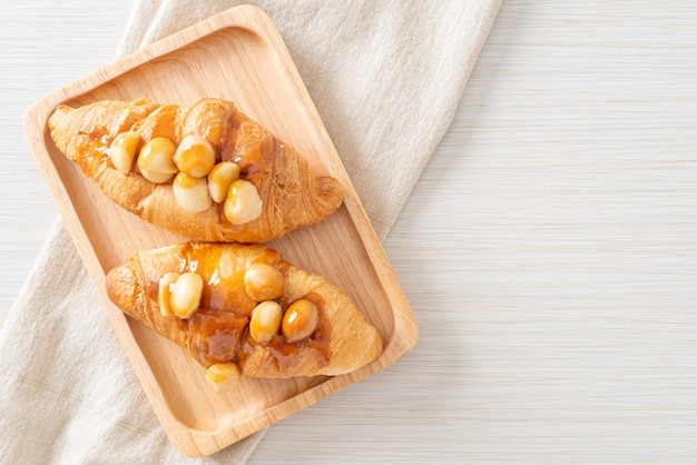 Croissant con macadamia y caramelo sobre placa de madera