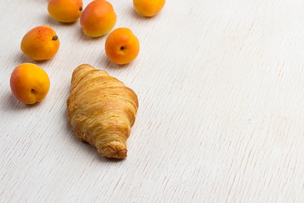 Croissant mit frischer Aprikose. Leckeres Frühstück. Weißer Hintergrund. Draufsicht. Speicherplatz kopieren