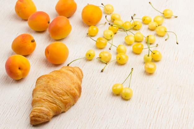 Croissant mit frischer Aprikose und gelber Kirsche.