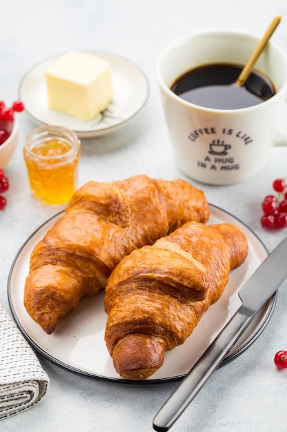 Croissant mit frischer Beerenbuttermarmelade und gresh Beeren mit Tasse Kaffee auf einem Teller Draufsicht