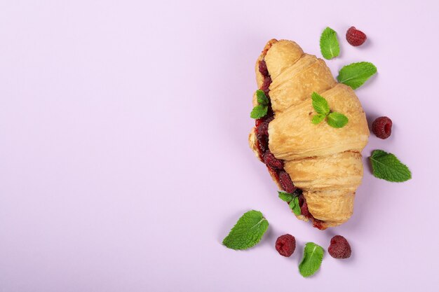 Croissant mit Himbeermarmelade auf violettem Hintergrund