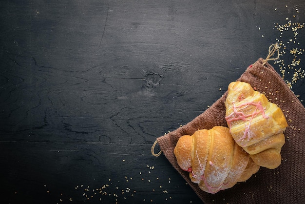 Croissant mit Joghurt Gebäckteig auf schwarzem Holzhintergrund Freier Platz für Text Ansicht von oben