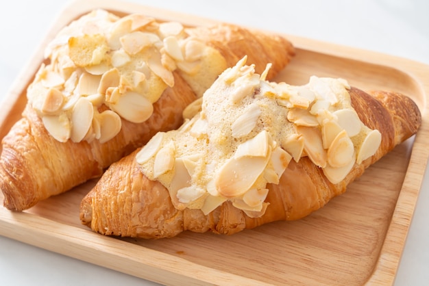 Croissant mit Sahne und Mandeln auf Holzteller
