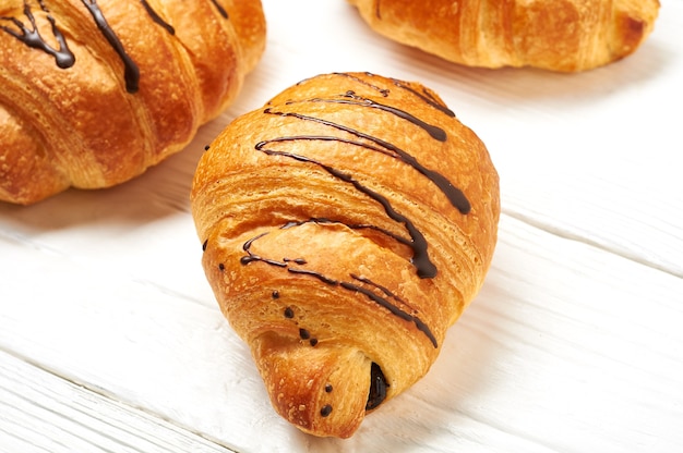 Croissant mit Schokolade auf weißem Holzhintergrund