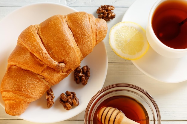 Croissant mit Tee und Honig auf einem weißen Tisch Draufsicht des Frühstücks