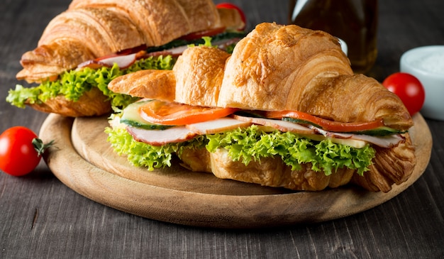 Croissant ou sanduíche fresco com salada, presunto no fundo de madeira.