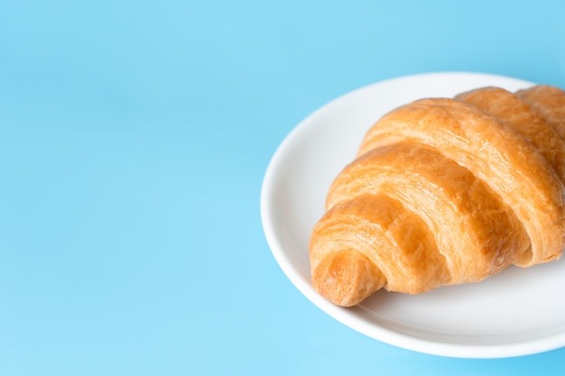 Croissant en un plato blanco sobre fondo de color