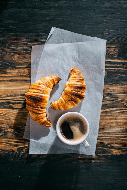 Croissant quente e fresco do conceito do café da manhã e uma xícara de café