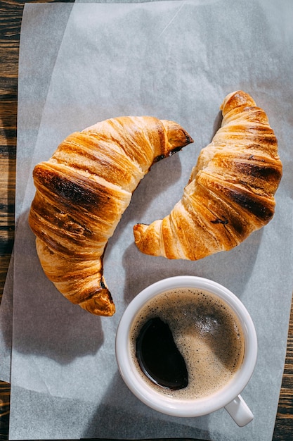 Croissant quente e fresco do conceito do café da manhã e uma xícara de café
