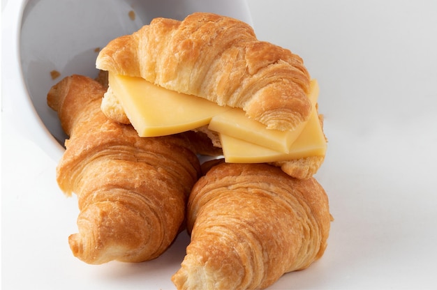 Croissant con queso aislado sobre fondo blanco.