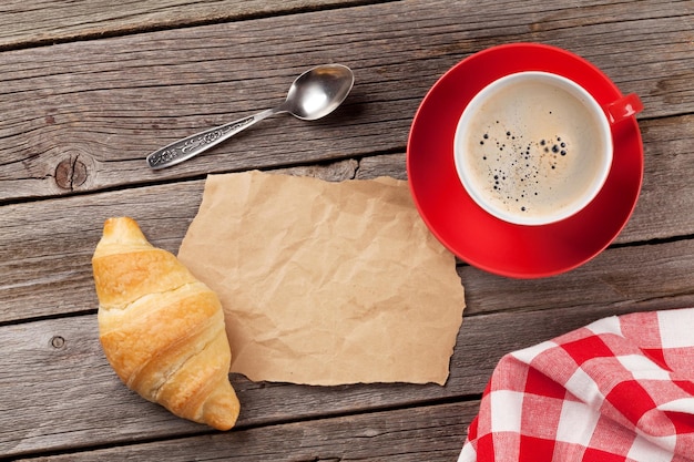 Croissant recién hecho y café en la mesa de madera