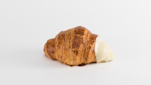 Croissant con relleno de crema sobre un fondo blanco.