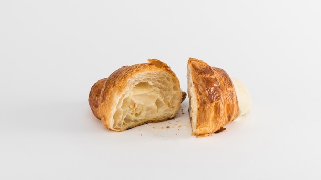 Croissant en rodajas con relleno de crema sobre un fondo blanco.