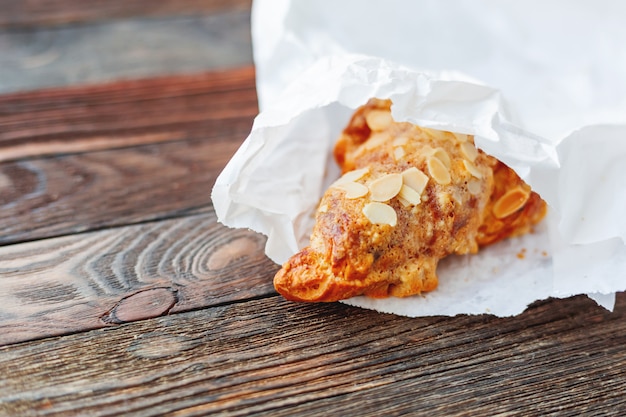 Croissant sabroso en bolsa de papel blanco sobre la mesa