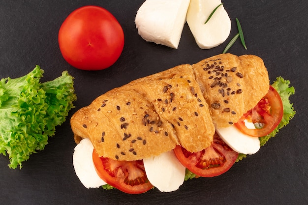 Croissant sandwich con lechuga mozzarella y tomate sobre piedra negra.