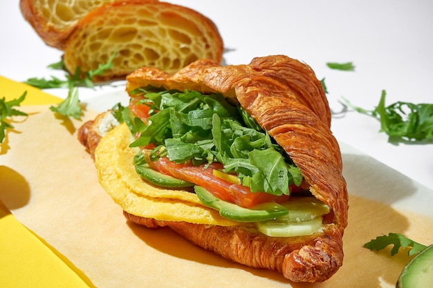 Croissant-Sandwich mit Lachsomelett und Avocado auf weißem Hintergrund Selektiver Fokus