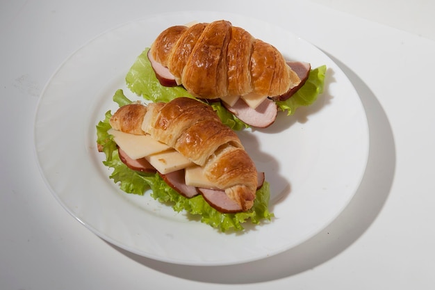 Croissant-Sandwich mit Schinken und Käse auf einem weißen Teller