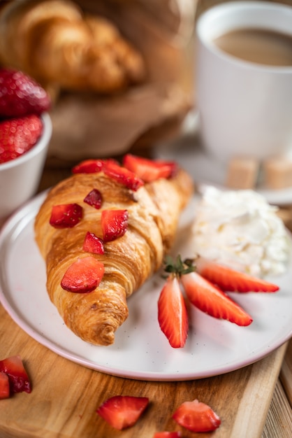 Croissant sándwiches y tazas de café en la mesa de madera