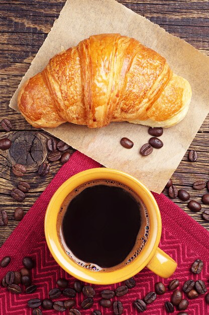 Croissant y taza de café en la mesa de madera