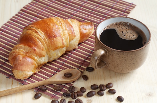 Croissant y taza de café sobre fondo de madera