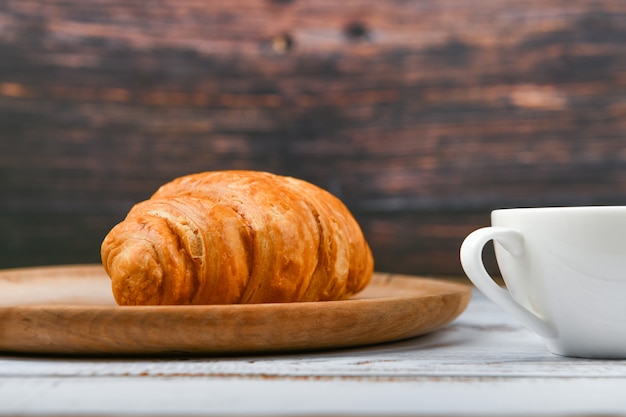 Croissant und eine Tasse Kaffee auf dem Tisch. Frisches französisches Croissant. Morgenfrühstück mit einem Croissant. Französisches Frühstück Ausgezeichnet hausgemacht. Frischer Turm.