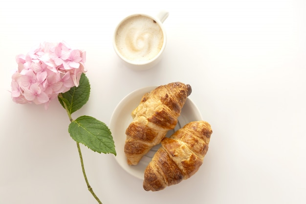 Croissant und eine Tasse Kaffee mit rosa Hortensie. Speicherplatz kopieren.