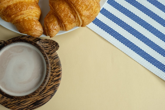 Croissant und heißer Kakao oder heiße Schokolade auf gelb