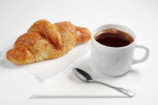 Croissant und Tasse heißen Kaffee zum Frühstück auf weißem Hintergrund