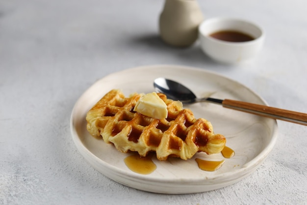 Croissant Waffle o croffle en plato blanco con mantequilla y miel