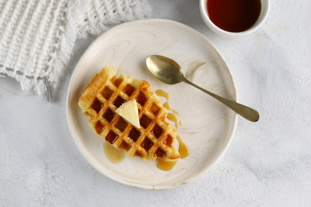 Croissant Waffle o croffle en plato blanco con mantequilla y miel