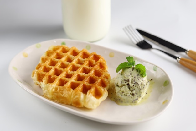 Croissant waffle ou croffle com sorvete de abacate servido no prato oval com colher e garfo