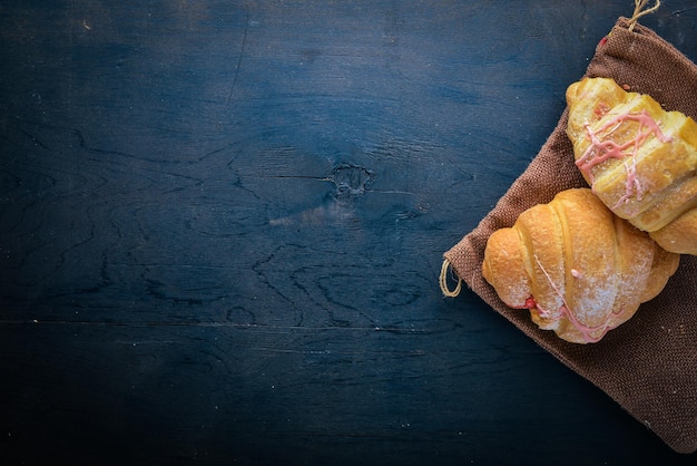 Croissant con yogur Masa de hojaldre Sobre un fondo de madera negra Espacio libre para texto Vista superior