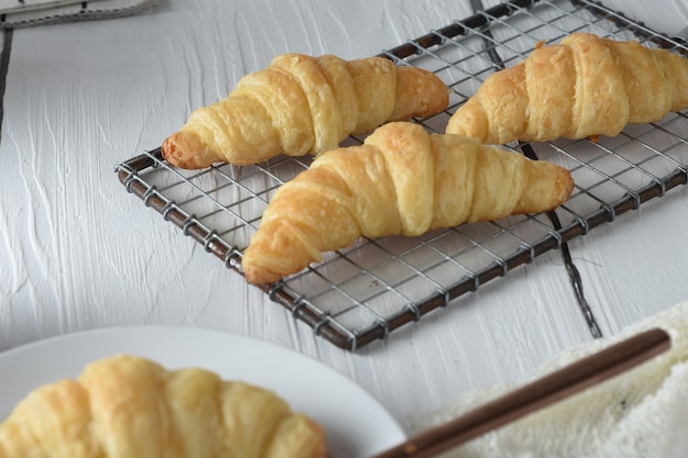 CroissantFrisch gebackene Croissants auf einem Tablett mit einem kleinen Glas Marmelade zum Frühstück