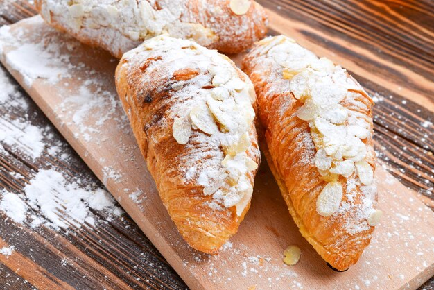 Croissants con almendras y té en una mesa de madera