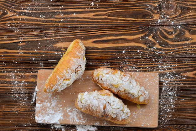 Croissants con almendras y té en una mesa de madera.