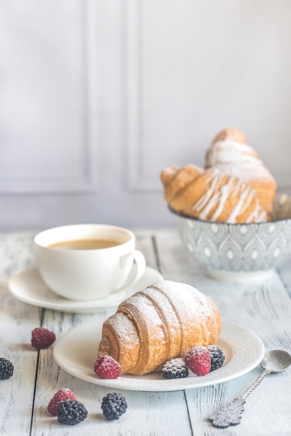 Croissants con bayas frescas y una taza de café.